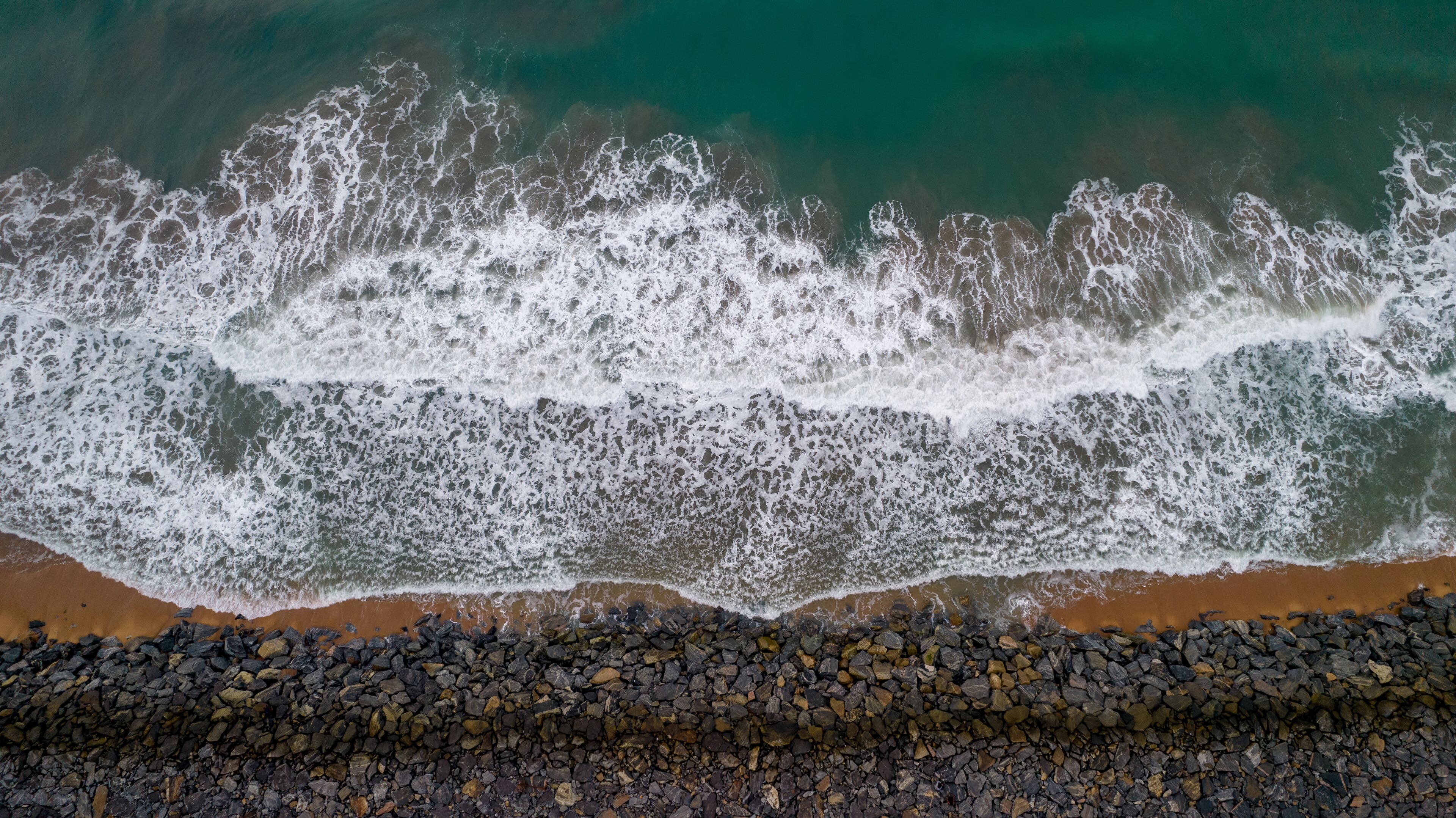 A rocky shoreline with waves crashing onto the beach.