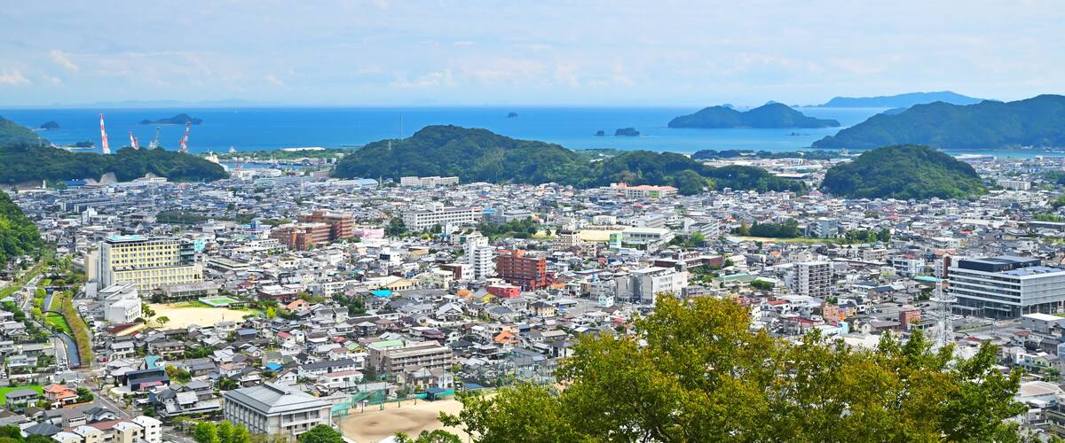 A coastal cityscape with dense urban development, a beach, and distant islands.