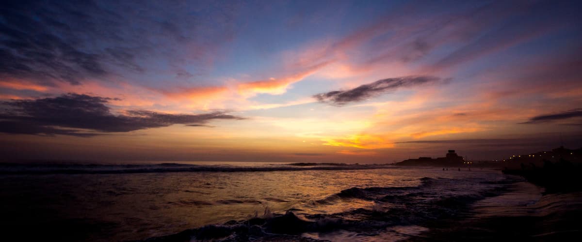 A sunset over a beach with waves crashing onto the shore.