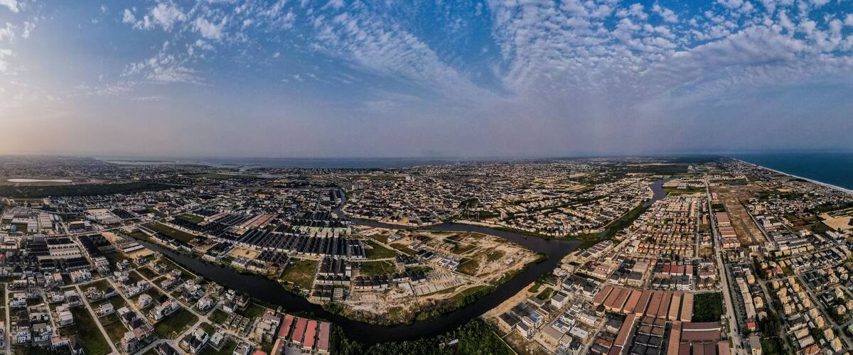 An aerial view of a coastal city with a river running through it, surrounded by residential areas and a large body of water.