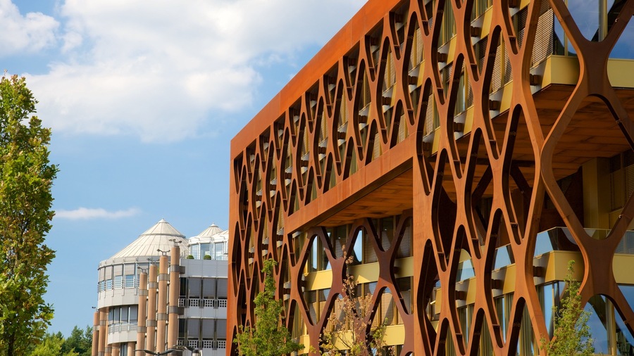 Un bâtiment moderne doté d’un complexe réseau de treillis en bois et, en arrière-plan, d’une structure en forme de dôme.
