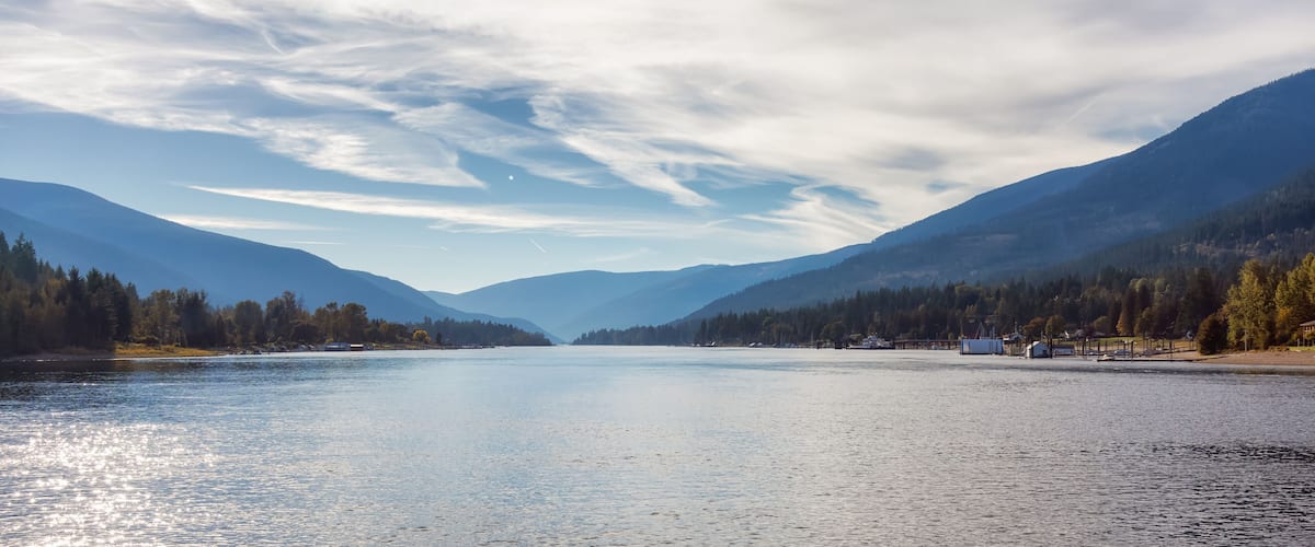 A calm lake surrounded by mountains and trees.