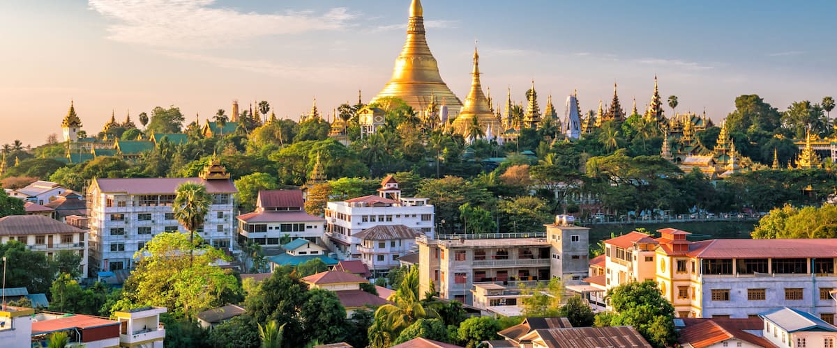 A golden stupa surrounded by lush greenery and traditional buildings.