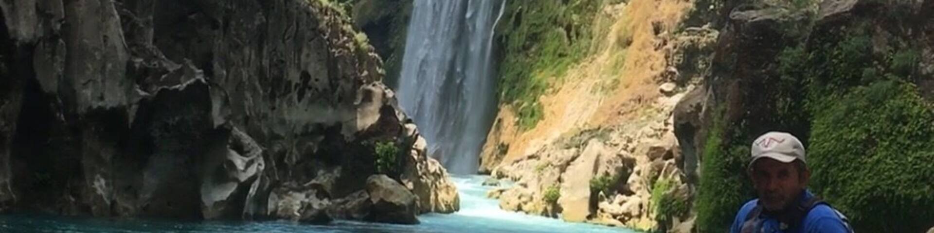 A person on a boat near a waterfall.