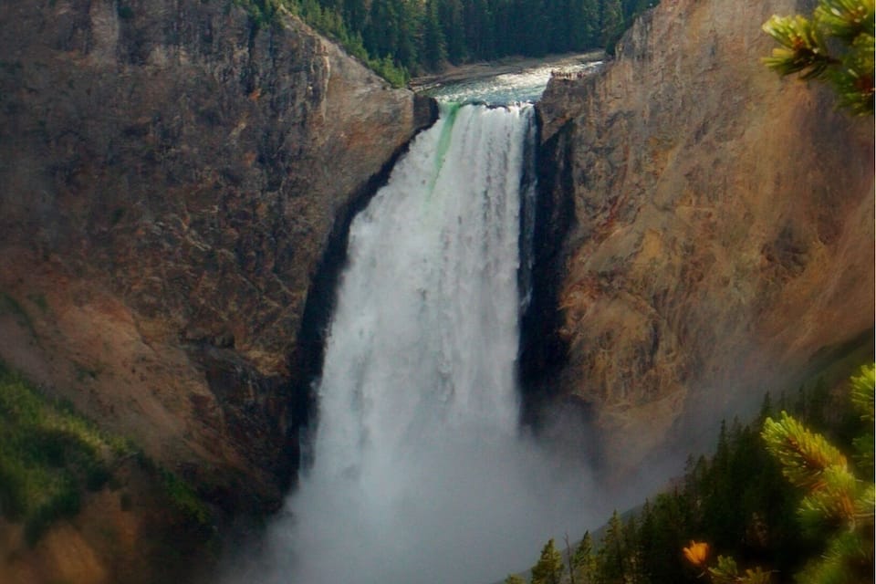 A waterfall cascading down a rocky gorge surrounded by dense forest.