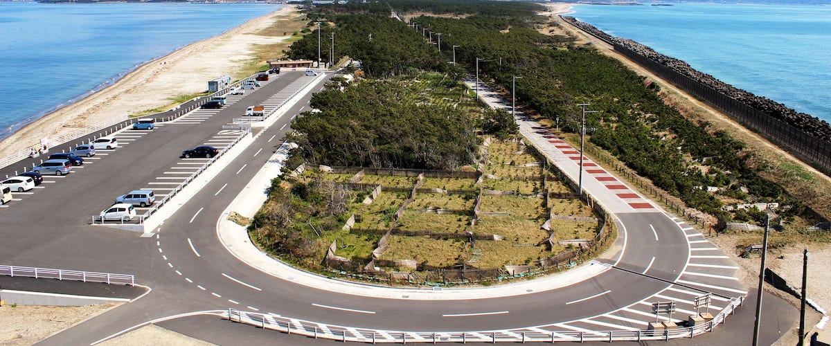 A coastal road with a roundabout, beach, and ocean.