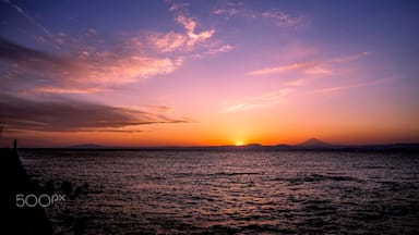 A sunset over a body of water with mountains in the distance.