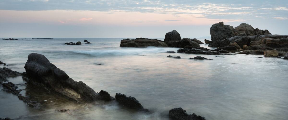 A rocky shoreline with large boulders and calm water.