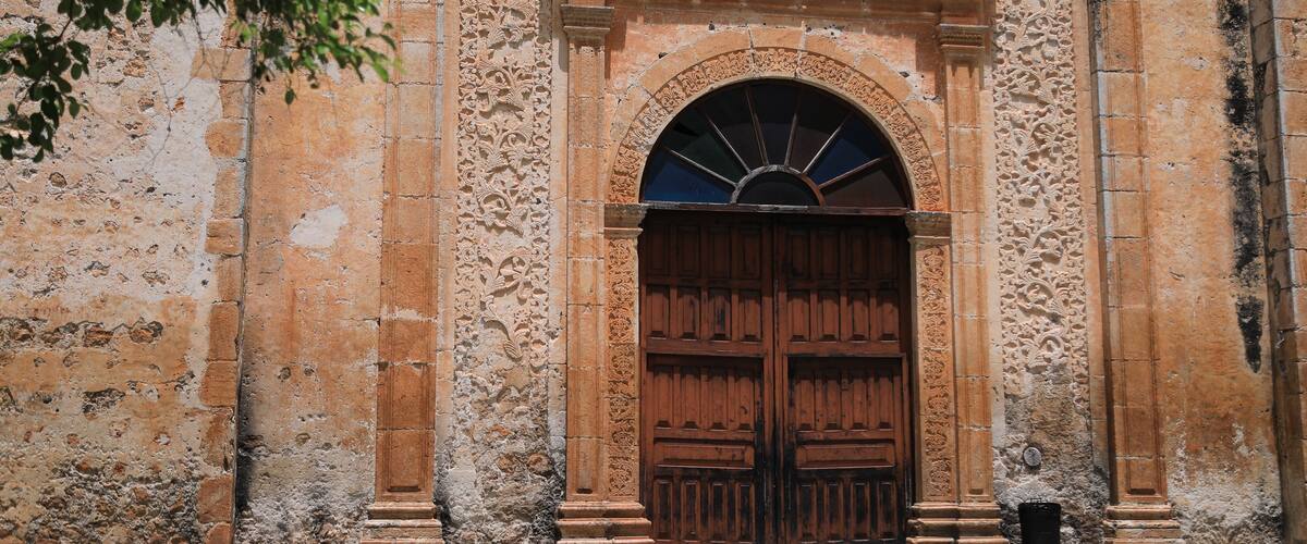 An ornate stone building with a large wooden door and intricate carvings.