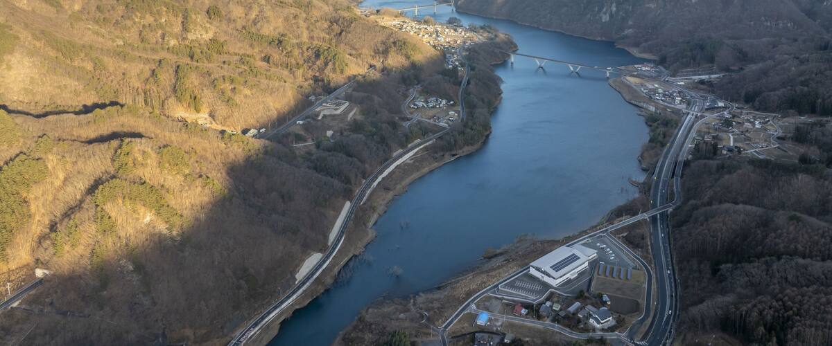 A river winding through a mountainous landscape with a bridge and roads.