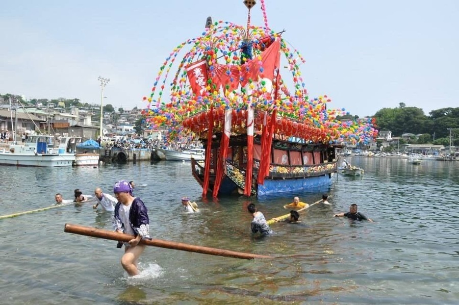 Kibune matsuri. Festival boats transport the portable shrine from one side of the harbor to the other. Boats are launched from the ramp using poles push/roll them into the water.