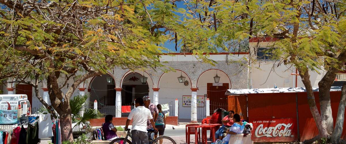 A street scene with a Coca-Cola advertisement, a bicycle, and people sitting at tables.