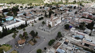 An aerial view of a town with a prominent church, a central plaza, and surrounding residential areas.