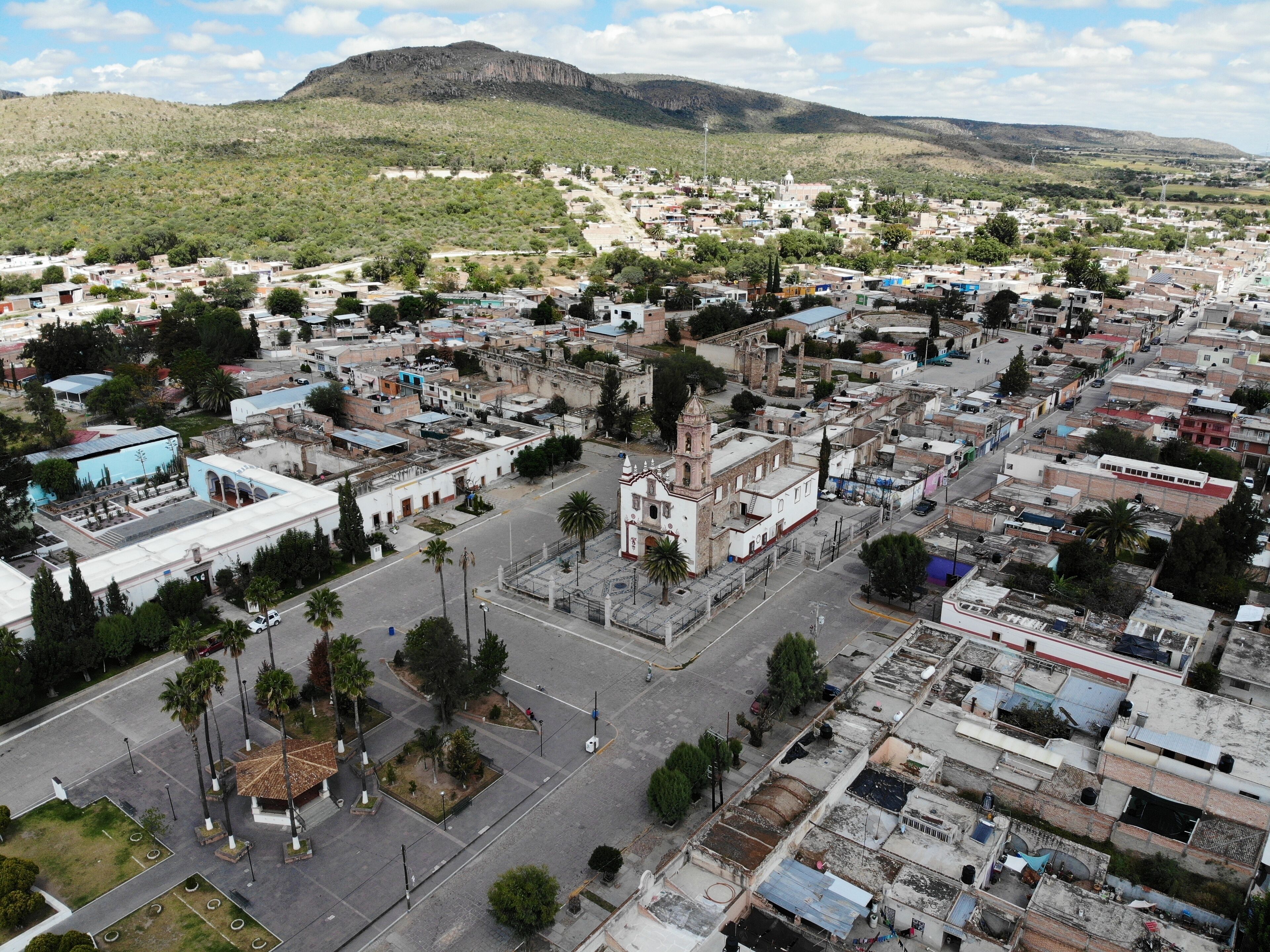 An aerial view of a town with a prominent church, a central plaza, and surrounding residential areas.