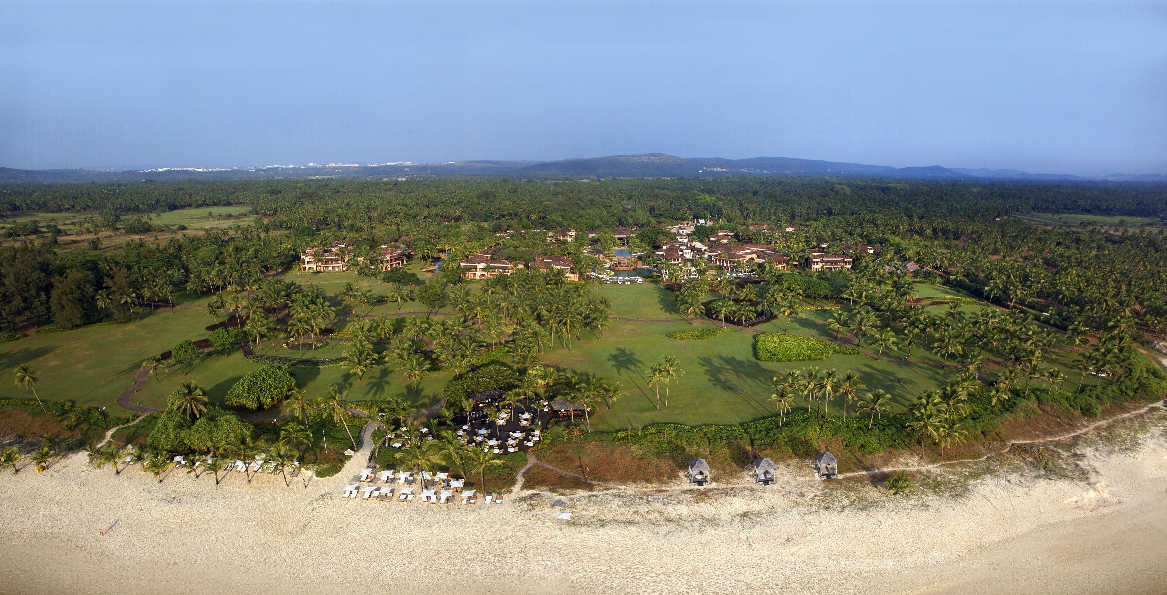 Bambolim, India - 17 November 2013: Aerial view of a luxurious resort nestled amidst lush green foliage, where terra-cotta roofs meet emerald lawns.