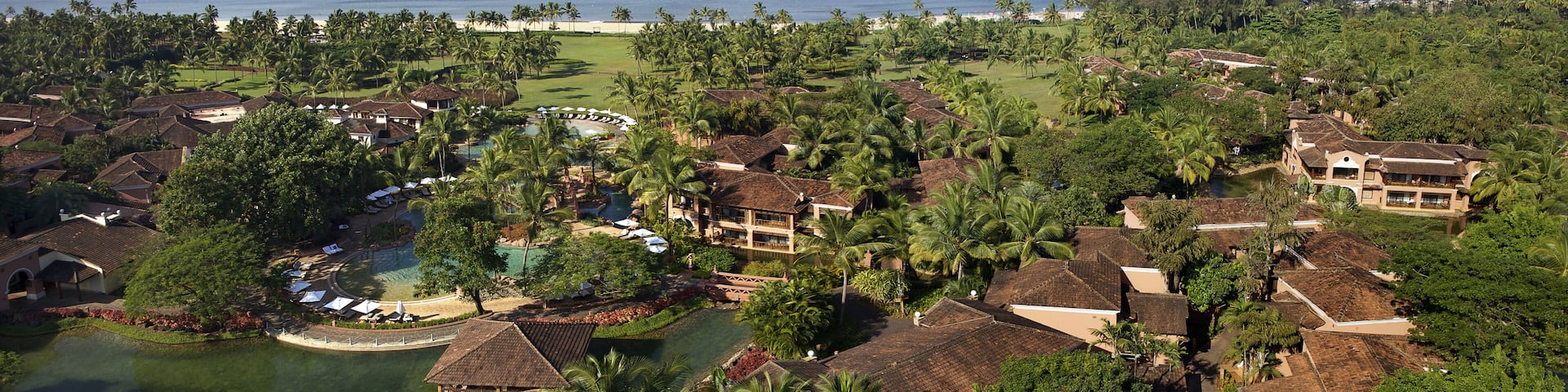 Bambolim, India - 18 November 2013: Aerial view of a coastal resort where terracotta roofs meet verdant palm trees, fringed by the azure Arabian Sea.