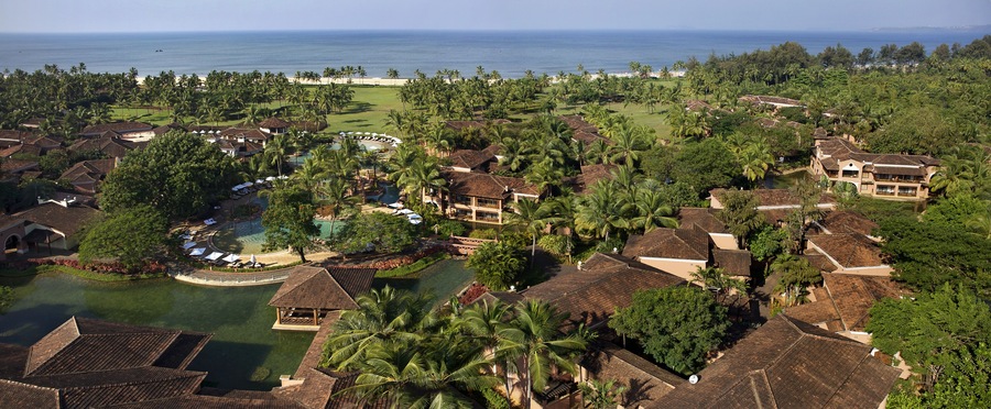Bambolim, India - 18 November 2013: Aerial view of a coastal resort where terracotta roofs meet verdant palm trees, fringed by the azure Arabian Sea.