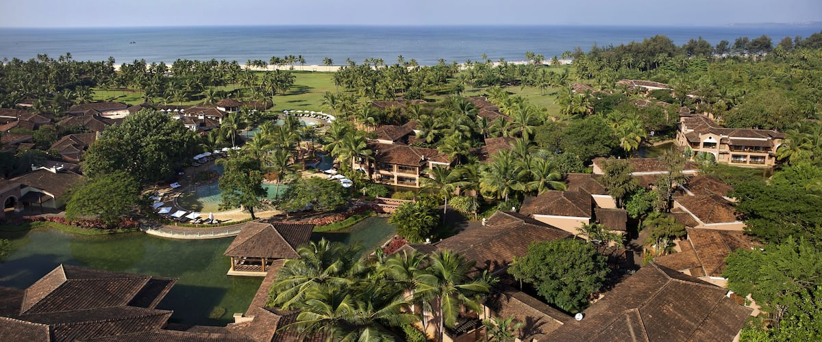 A resort with a pool, palm trees, and a view of the ocean.