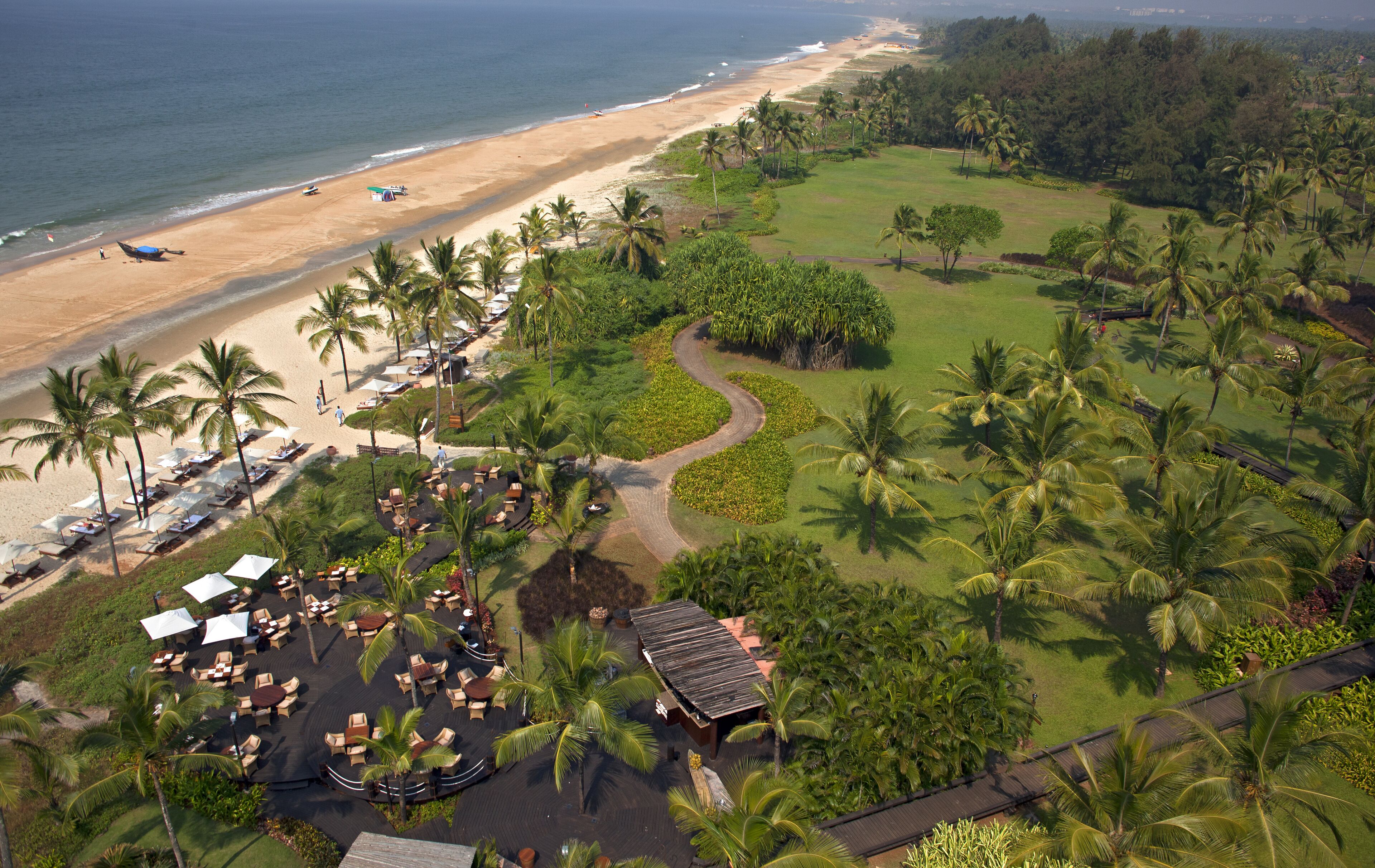Bambolim, India - 19 November 2013: Aerial view of sun-kissed sands meeting emerald lawns, dotted with swaying palms and the inviting allure of a coastal resort.