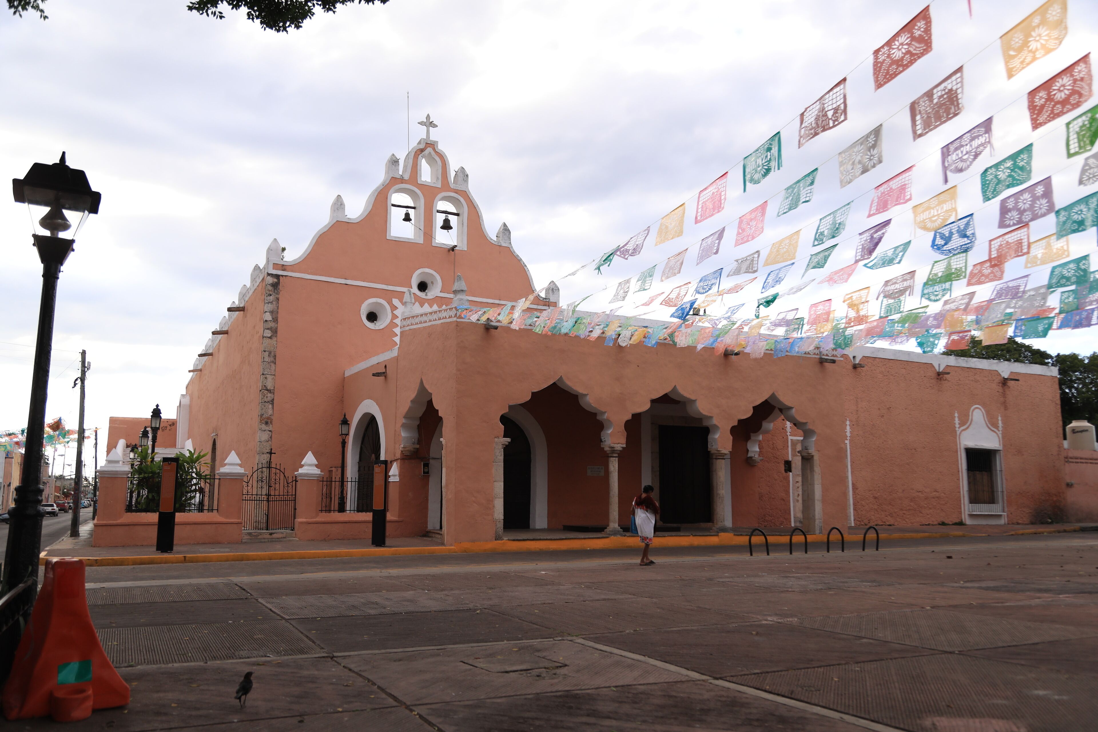 A pink building with arches and a bell tower, decorated with colorful flags.