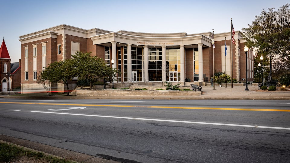 A courthouse with a red roof, columns, and flags.