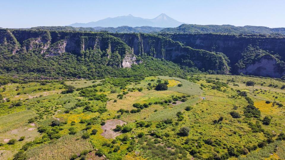 A lush valley with terraced fields and a mountain range in the background.