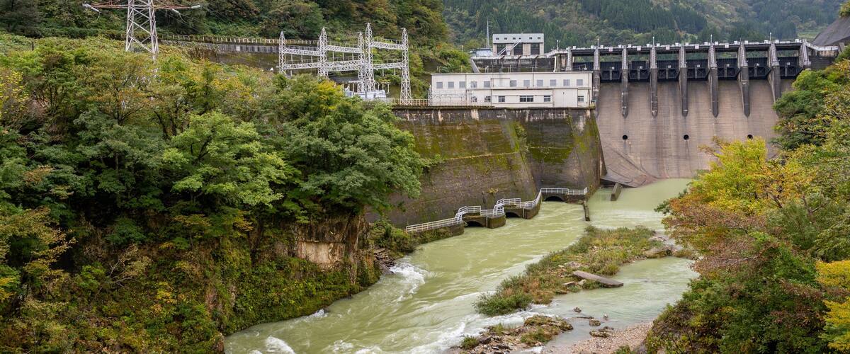 A hydroelectric dam with a river flowing through a forested valley.