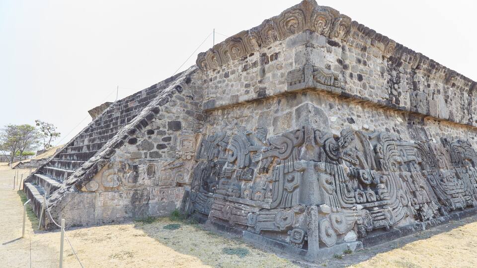 A large stone pyramid with intricate carvings and a staircase leading up to the top.