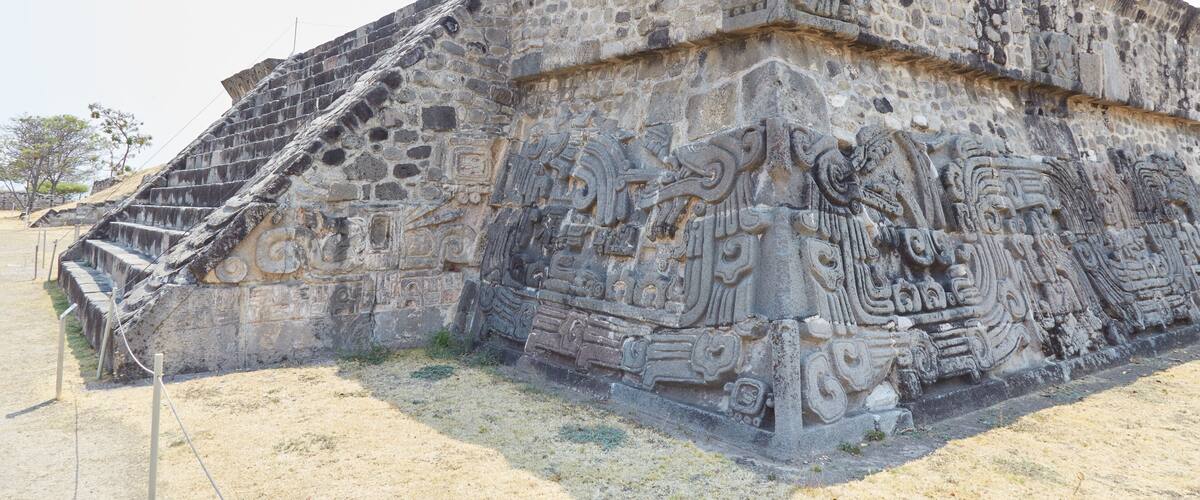 A large stone pyramid with intricate carvings and a staircase leading up to the top.