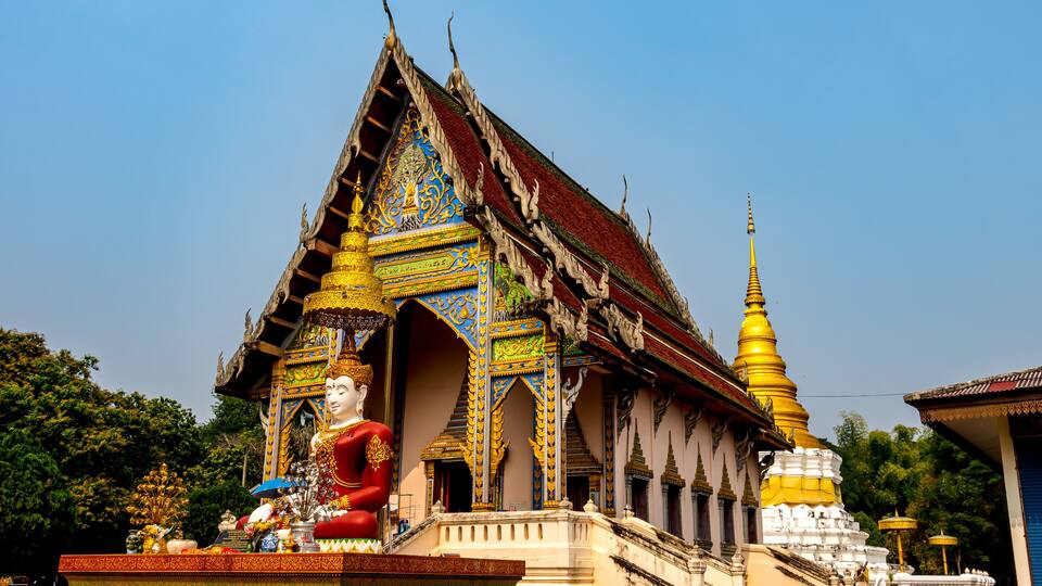 A temple with intricate architecture, a large Buddha statue, and a golden stupa.