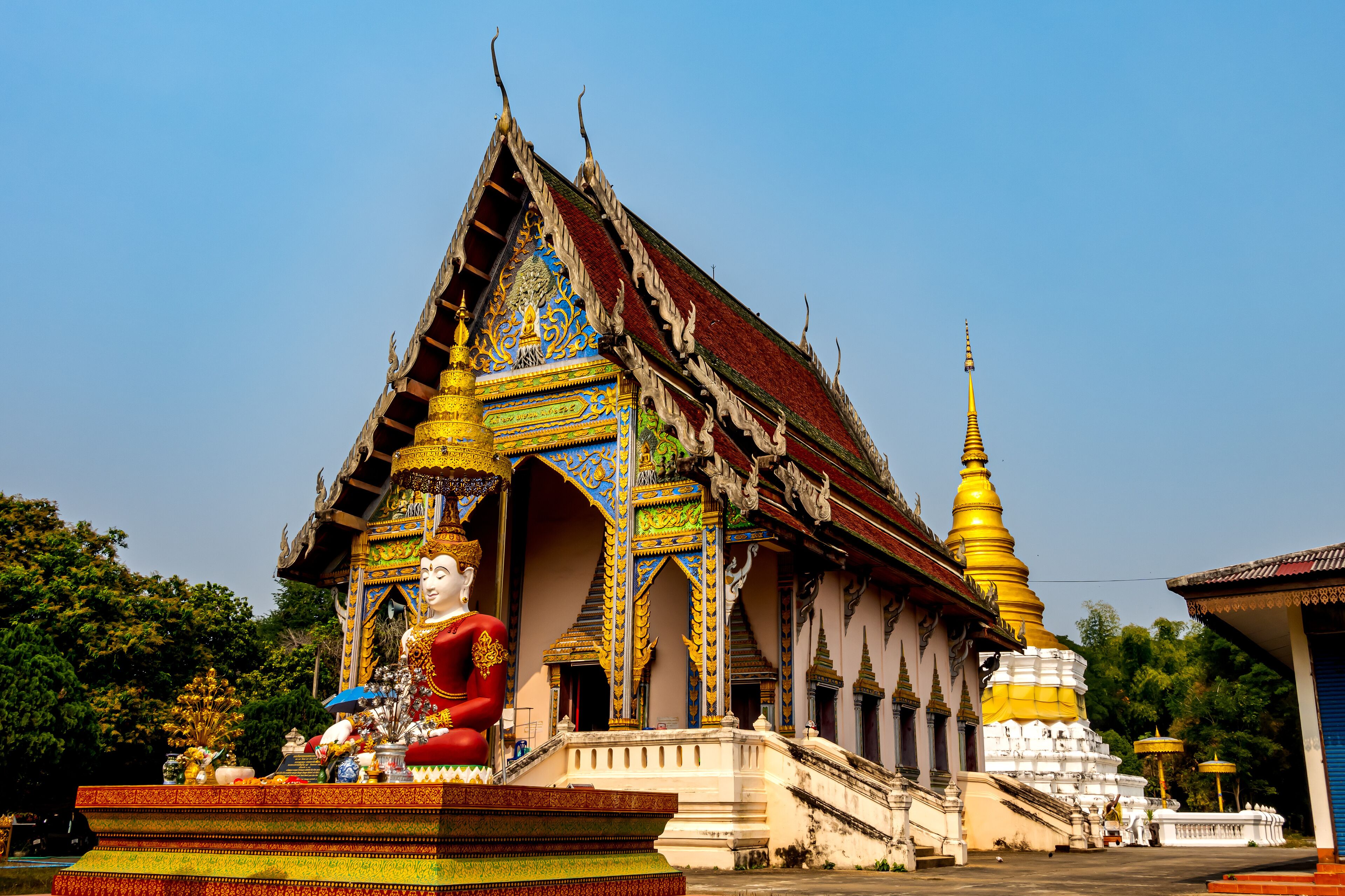 A temple with intricate architecture, a large Buddha statue, and a golden stupa.