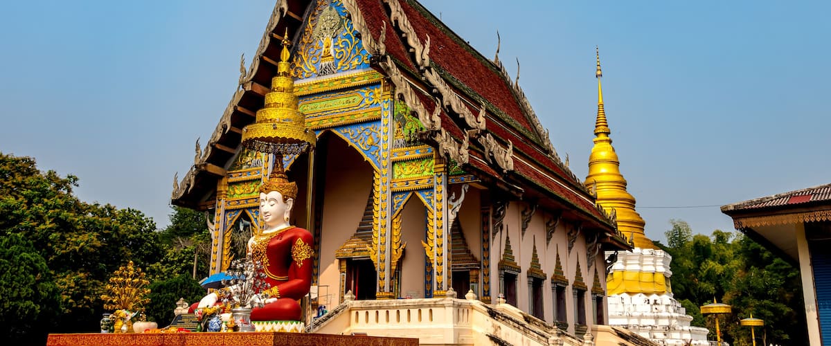 A temple with intricate architecture, a large Buddha statue, and a golden stupa.
