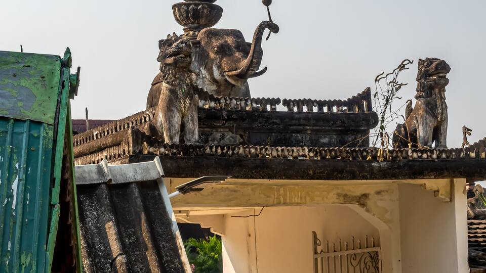 A traditional temple with ornate decorations, including a large circular emblem and statues of lions.