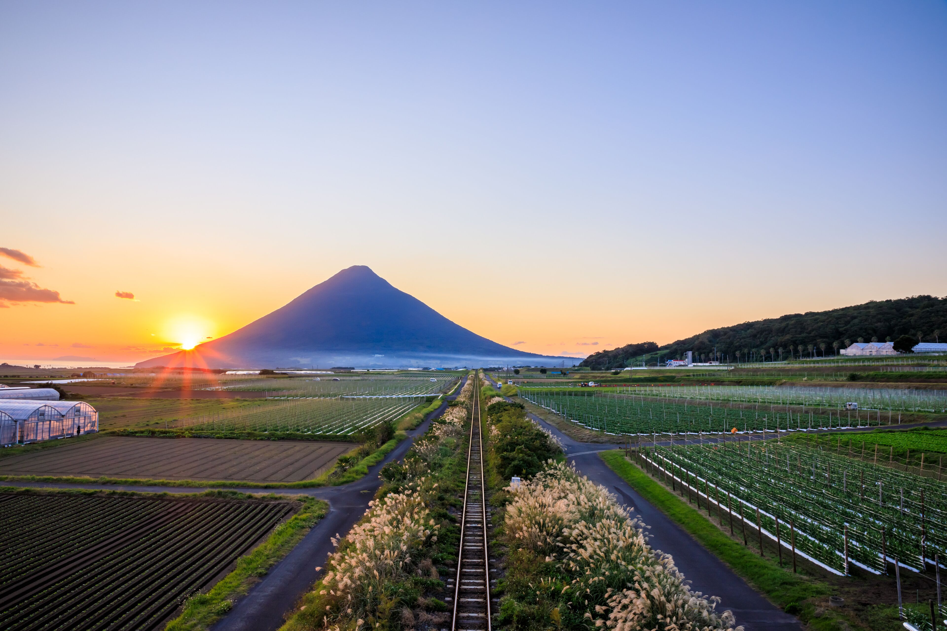 秋の開聞岳と指宿枕崎線と夕日　鹿児島県指宿市　Mt. Kaimondake, Ibusuki Makurazaki Line and sunset in autumn. Kagoshima Pref, Ibusuki City.