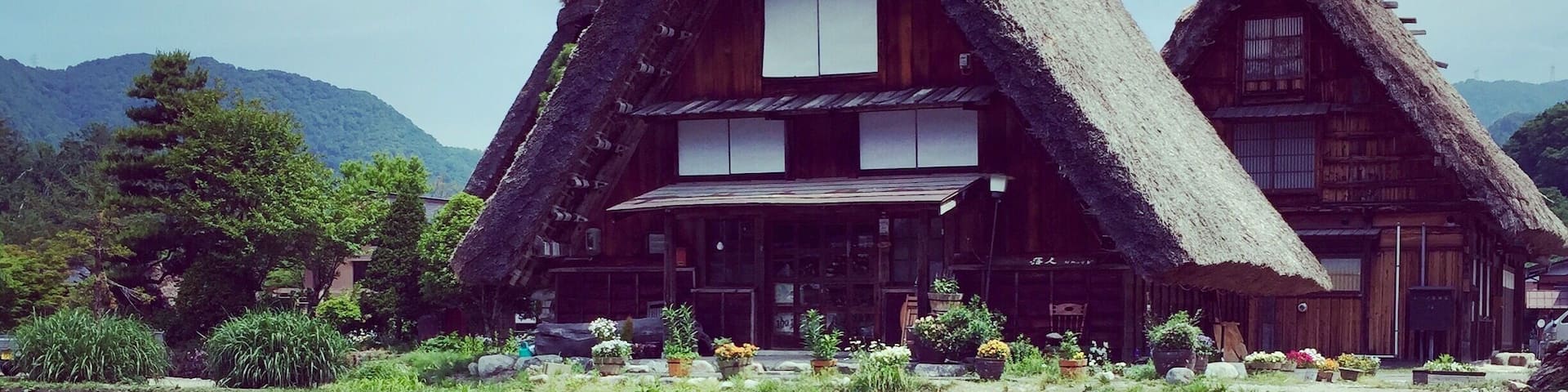 A traditional thatched-roof house with a pond in front.
