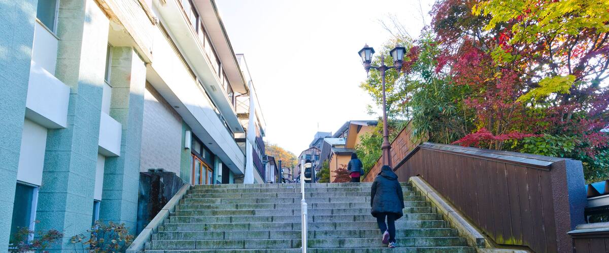 A set of stone steps leading up a hill, surrounded by buildings and trees with autumn foliage.