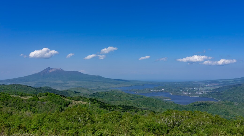 A mountain with a clear sky and scattered clouds.