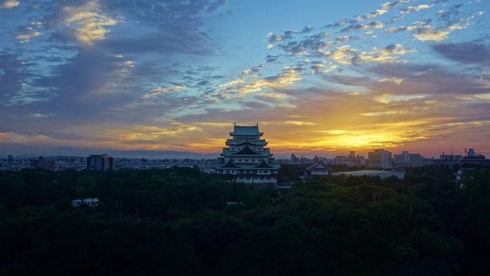 Eine traditionelle japanische Pagode im Abendlicht, mit einer Stadtlandschaft im Hintergrund.