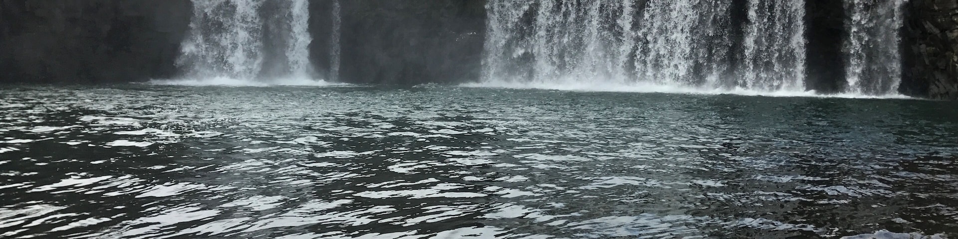 Una gran cascada que se precipita en una masa de agua rodeada de acantilados rocosos.