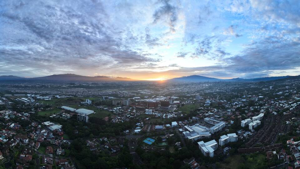 A cityscape at sunset with mountains in the background.