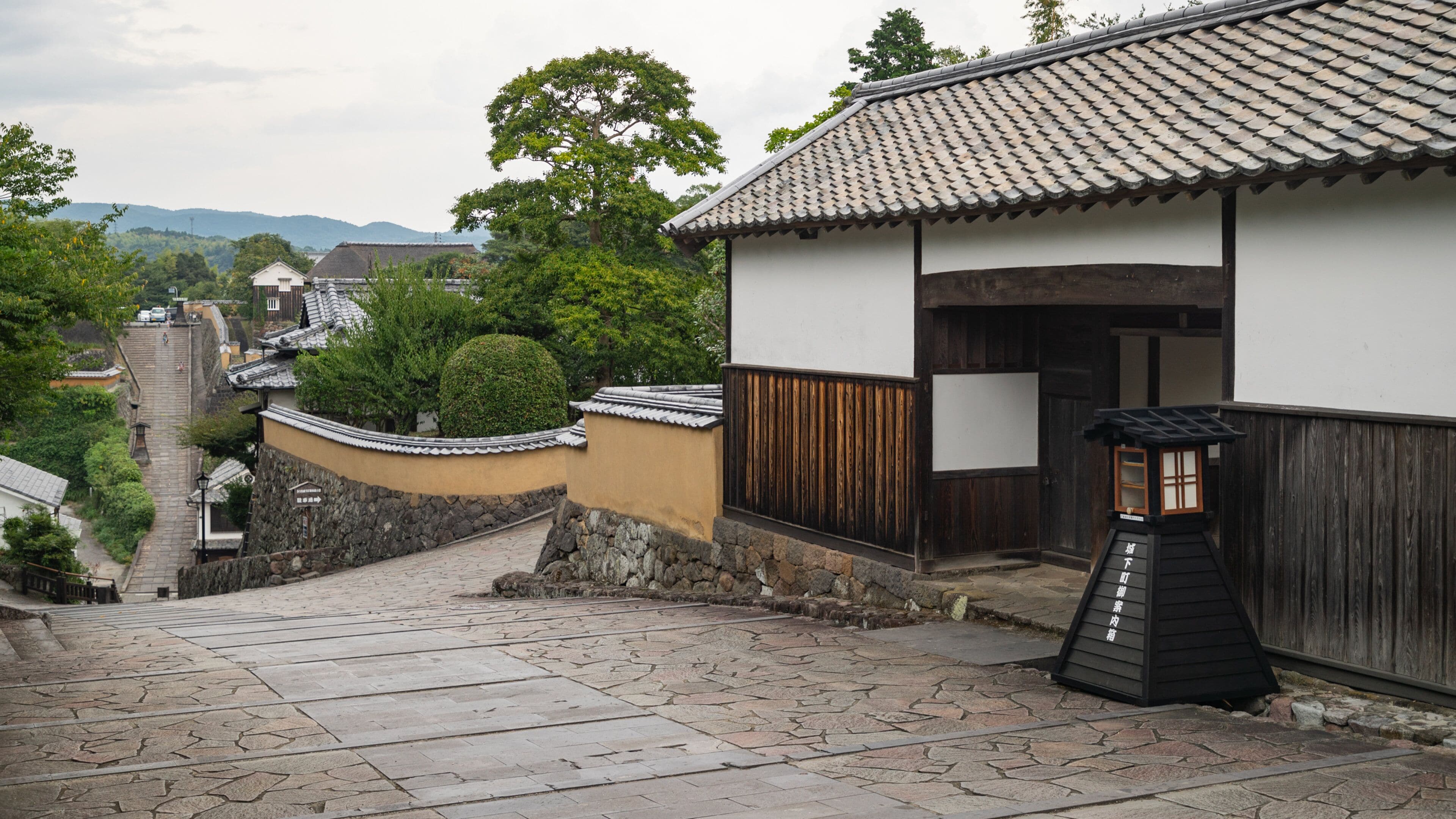 A traditional Japanese street with stone steps leading up to a wooden gate.