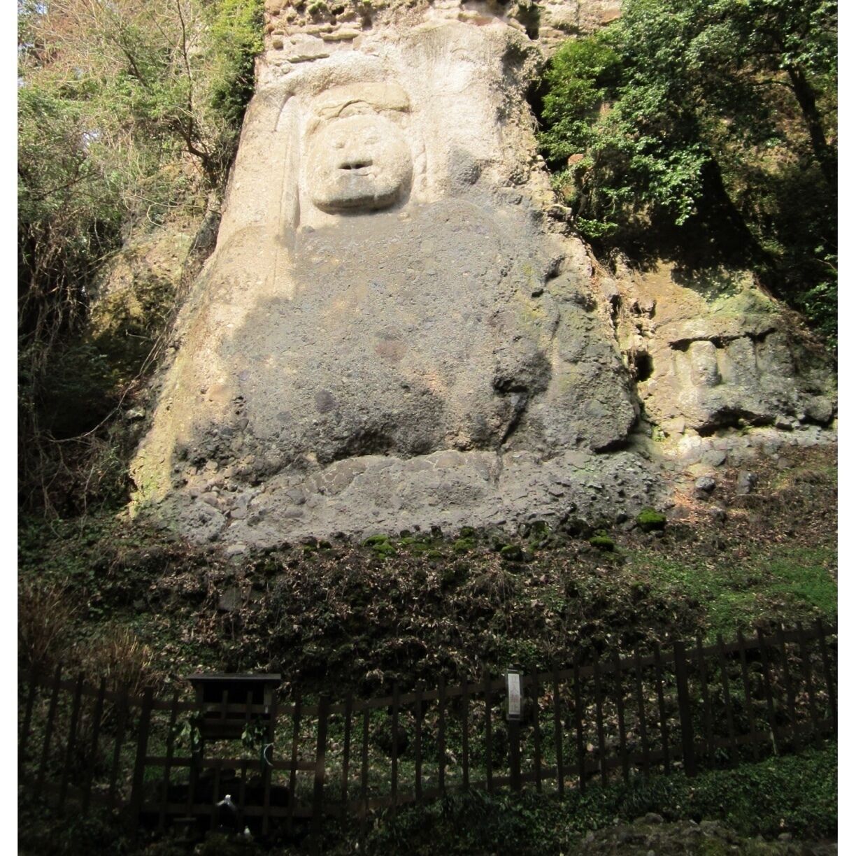 A large rock face with a carved Buddha statue.