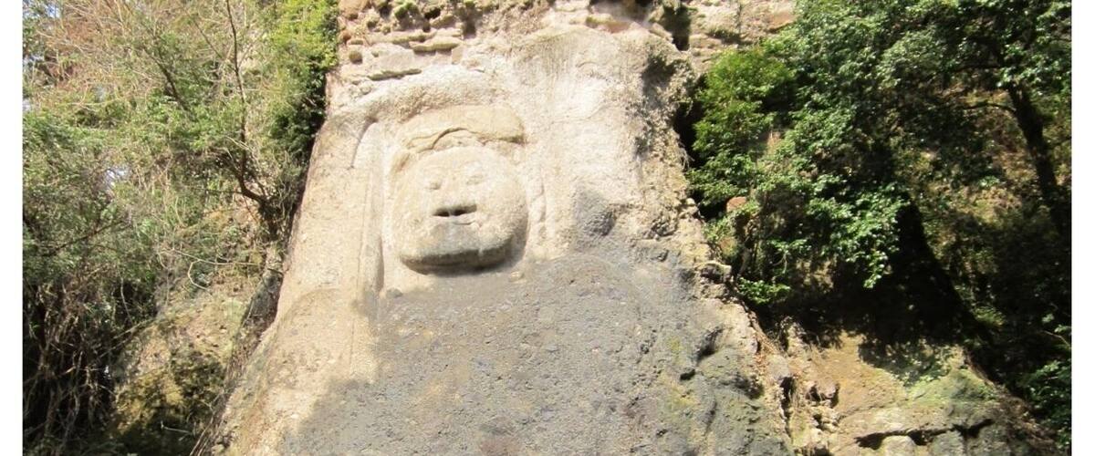 A large rock face with a carved Buddha statue.
