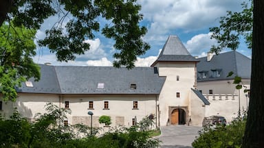 A castle with a tower, surrounded by greenery and a clear sky.