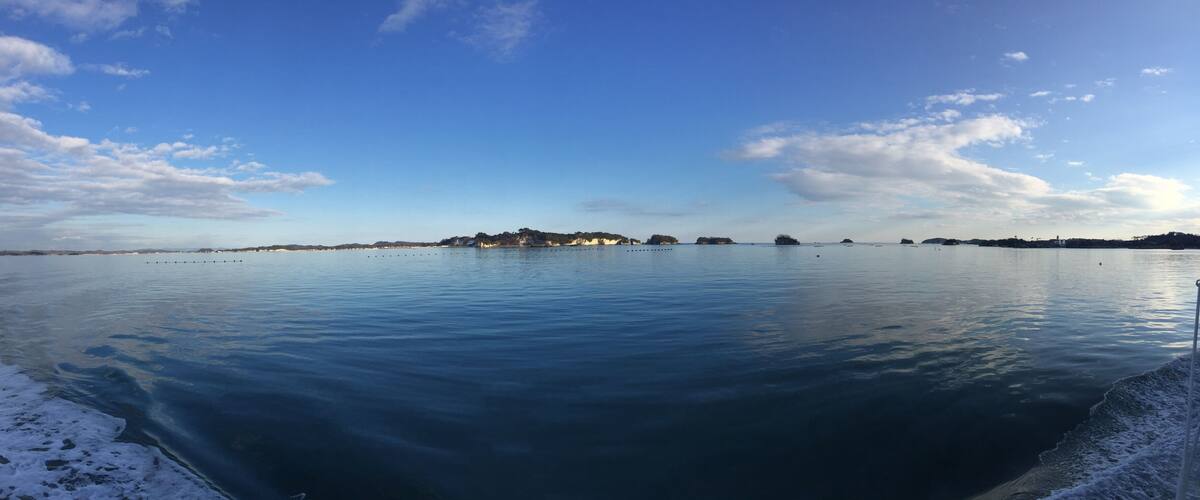 A calm lake with a small island in the center and a clear sky.