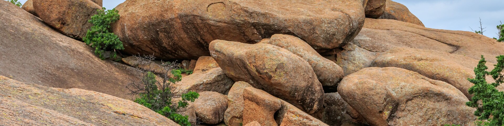 Paisagem acidentada com grandes pedras e vegetação rasteira.