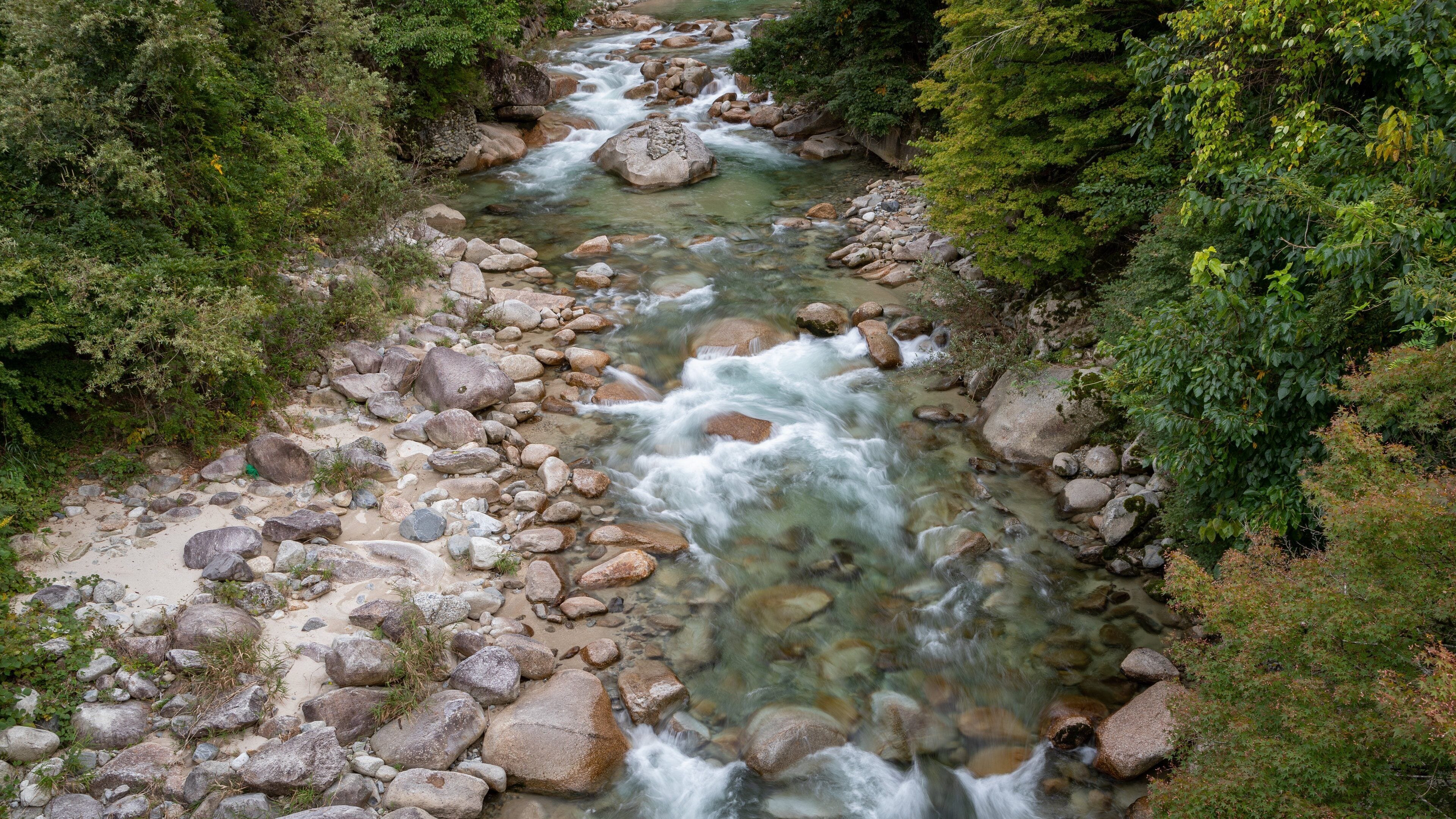 A river flowing through a rocky landscape with dense greenery on both sides.