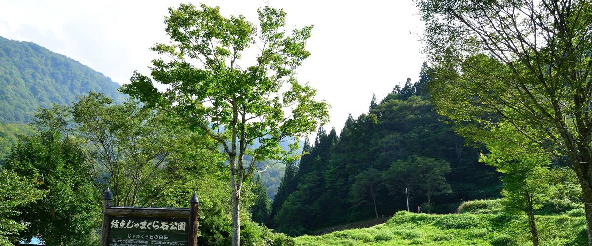 A sign in a lush green landscape with a small wooden structure.