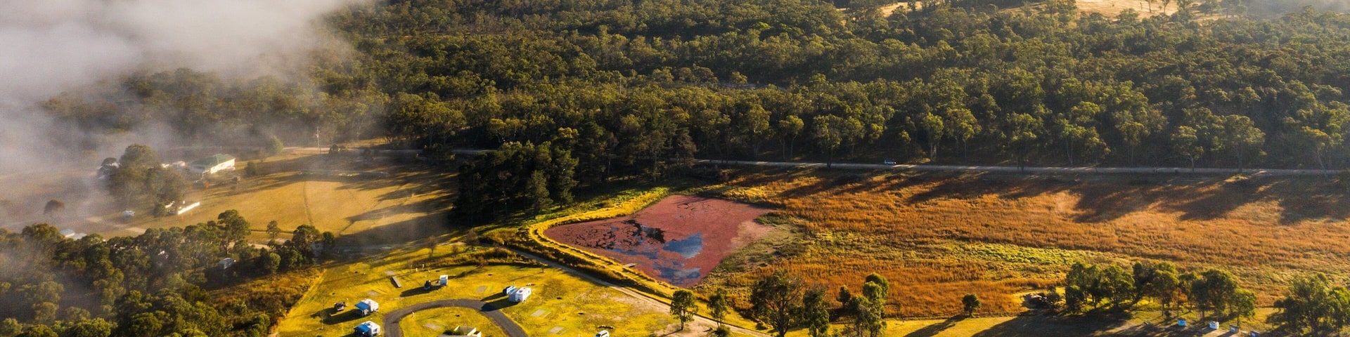 A forested landscape with a clearing and a small building.