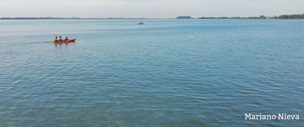 A calm body of water with kayaks and a distant boat.